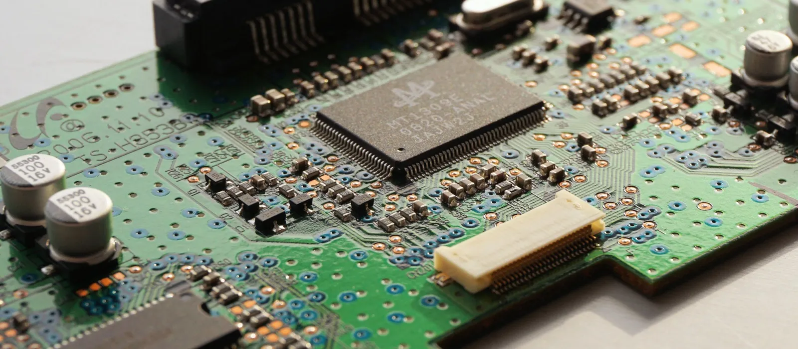Green printed circuit board with components on a white surface