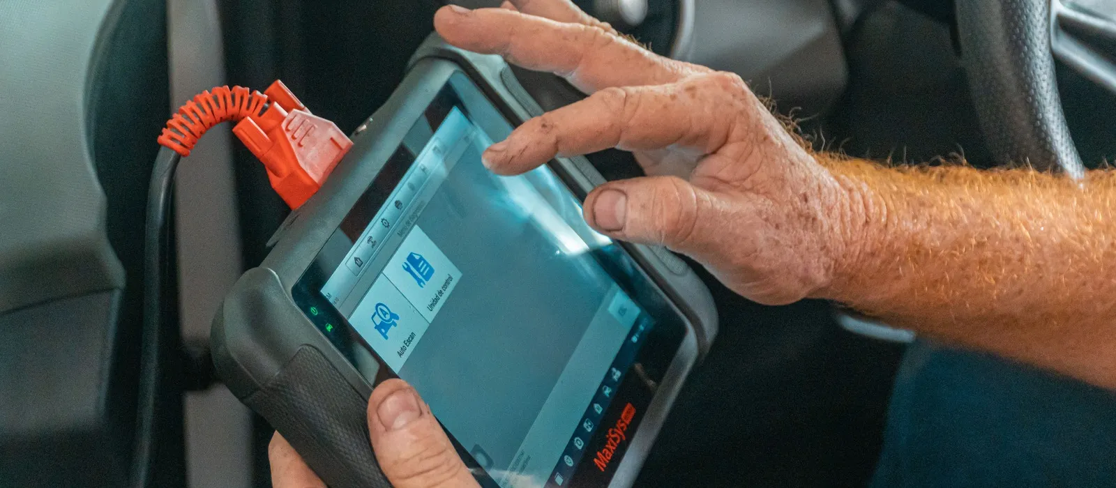 Technician holding a diagnostic scan tool inside a vehicle