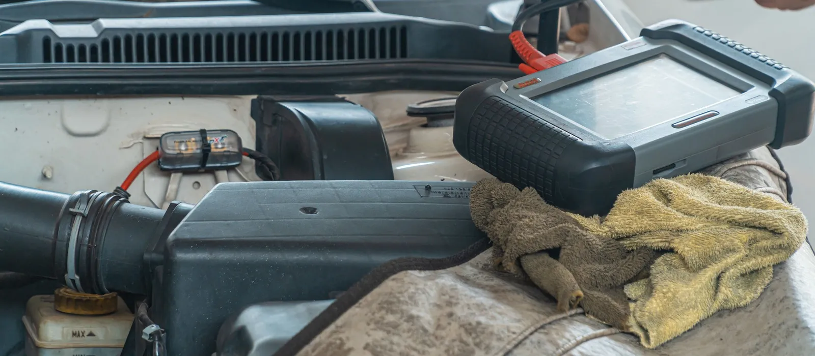 Diagnostic scan tool resting on a vehicle engine cover