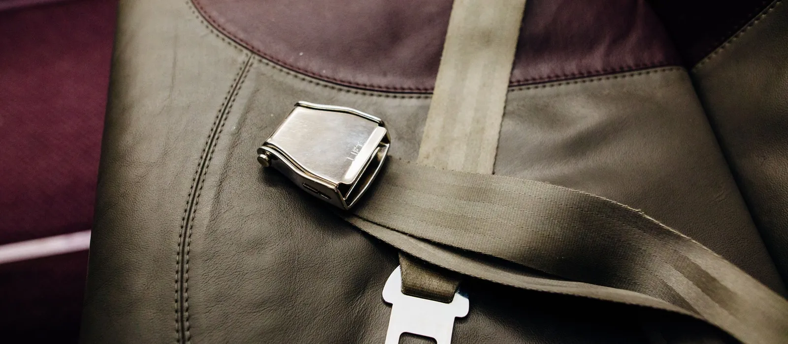 Seat belt buckle and latch plate resting on a leather car seat
