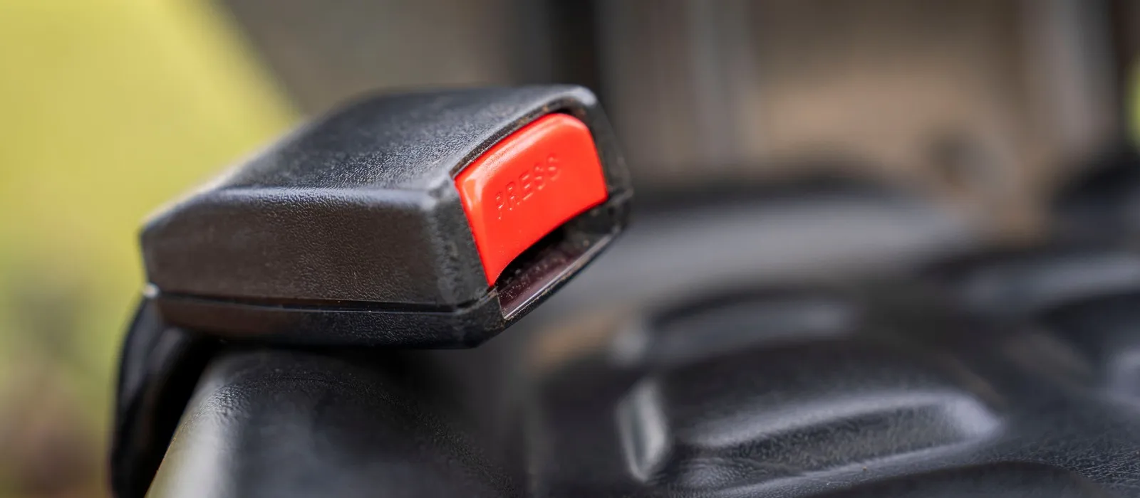 Seat belt buckle with a red release button on a car seat