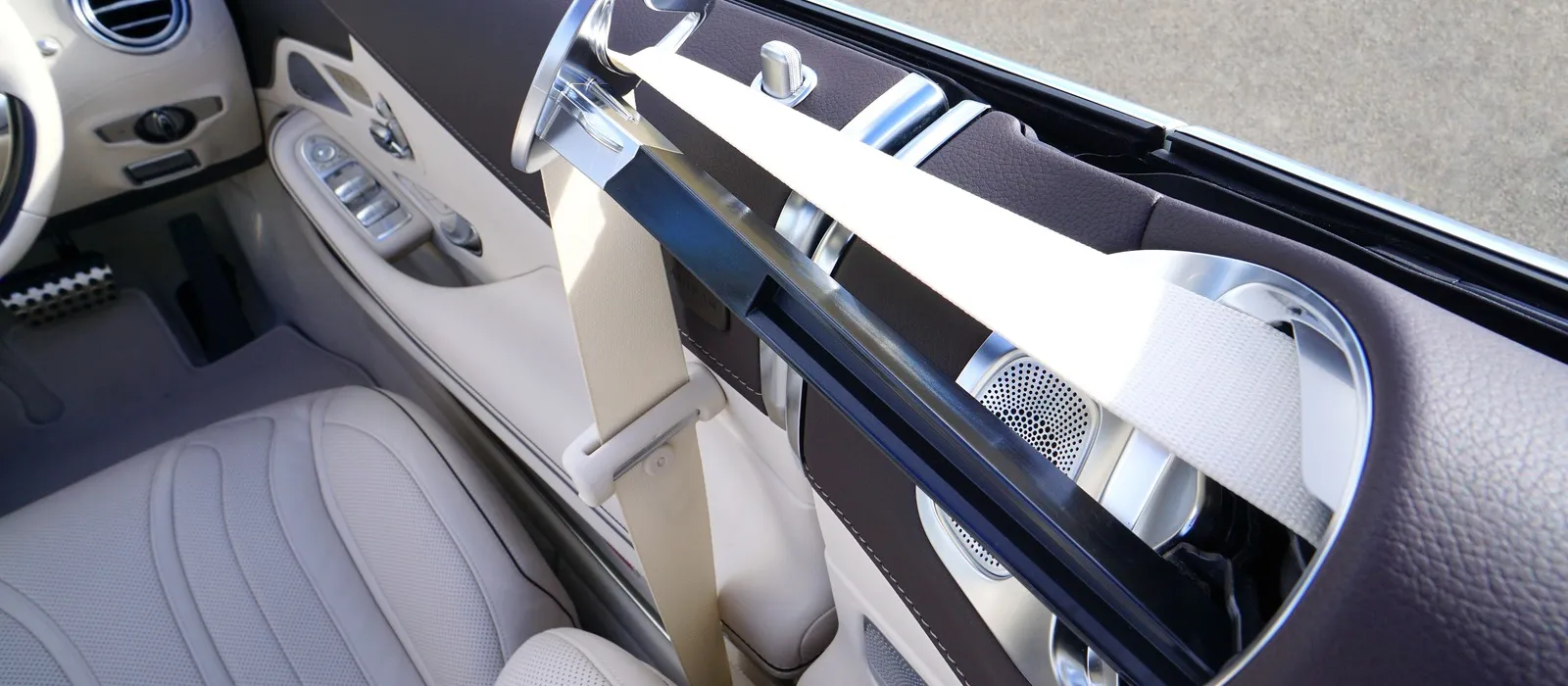 Seat belt webbing passing through a chrome guide on a car seat
